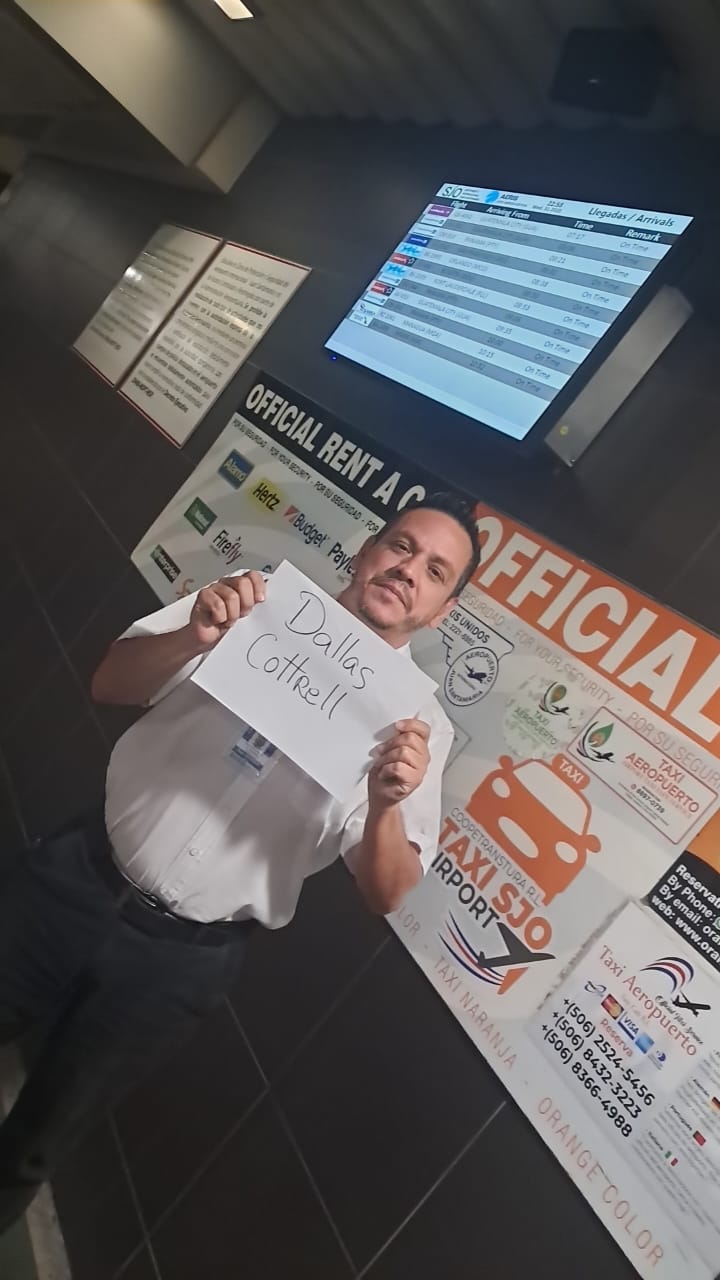 Mario Artavia Private shuttle driver at SJO Airport meeting point holding a name sign to welcome arriving passengers.